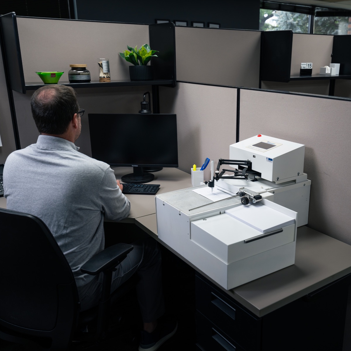 UniProd handwriting machine operating beside a desk in an office