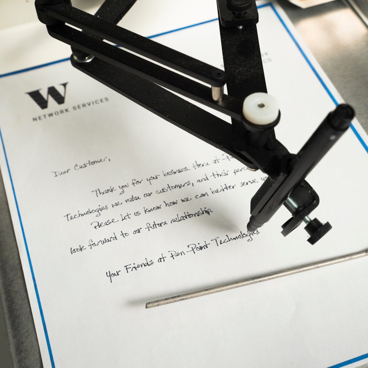 Close view of UniProd using a ballpoint pen to write a personalized letter